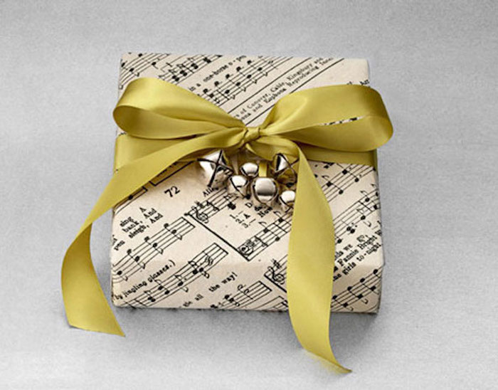 kis ajándék, papírra csomagolva zenei jegyekkel, harangdíszítéssel
