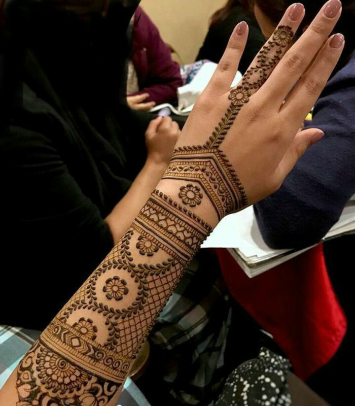 Γυναίκες τατουάζ σε όλο το χέρι και το αντιβράχιο με πολλά μικρά στολίδια του χρώματος χέννα, δαχτυλίδι δαχτυλίδι δάχτυλο