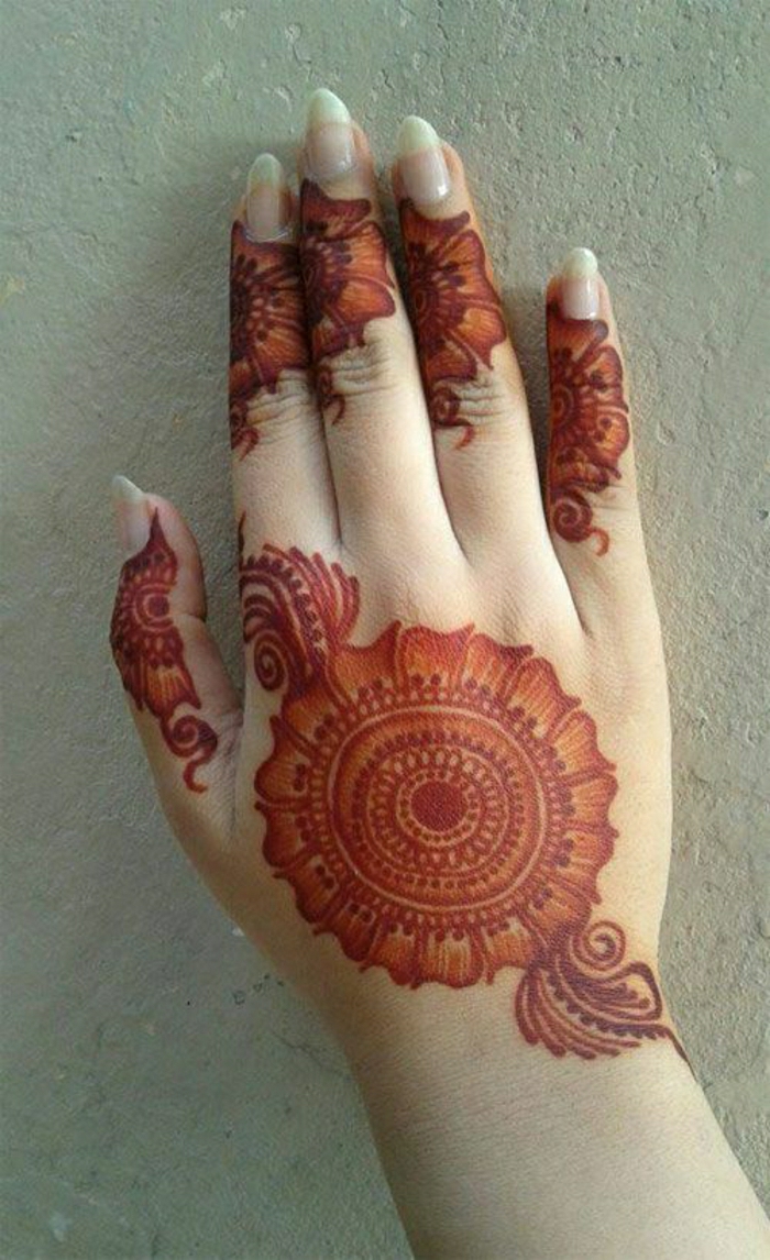 προσωρινή τατουάζ κόκκινο henna στην επιφάνεια του χεριού μιας γυναίκας με μακριά νύχια, floral τατουάζ