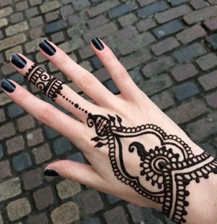 Γυναίκα με τατουάζ χένας στο χέρι της και στο μεσαίο δάχτυλο σε μαύρο, μαύρο βερνίκι νυχιών