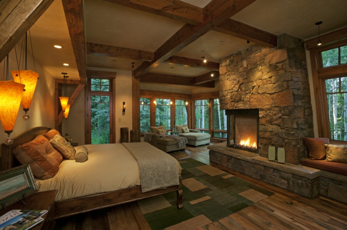 门牌石木舒适的卧室的壁炉和典雅的床单椅乡村风格