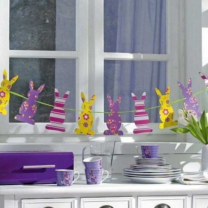 Los conejitos de Pascua cuelgan de forma colorida y decoran alegremente la ventana