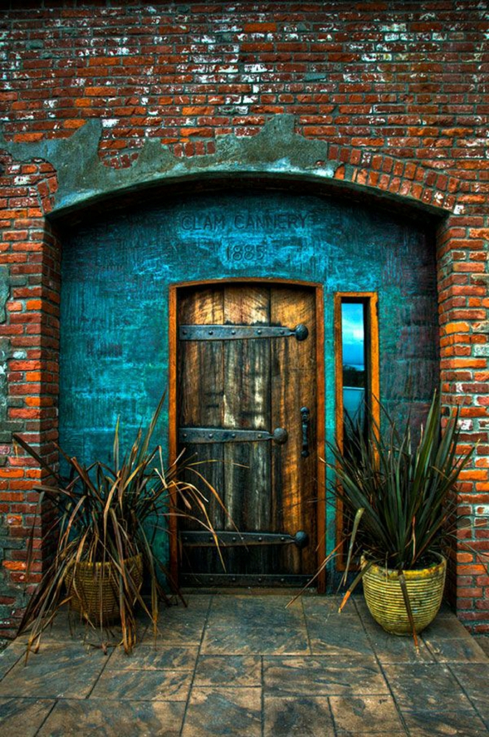стари входни врати дървени метални орнаменти тухлена сграда саксии за цветя