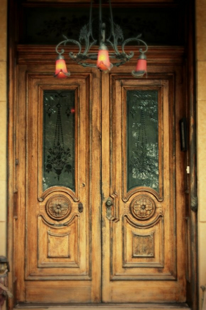 стари дървени врати пред масивен полилей от стъкло