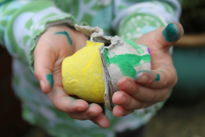 Piszkos kéz a gyermek, aki hordoz két tojás karton - Húsvéti kézműves tojás karton