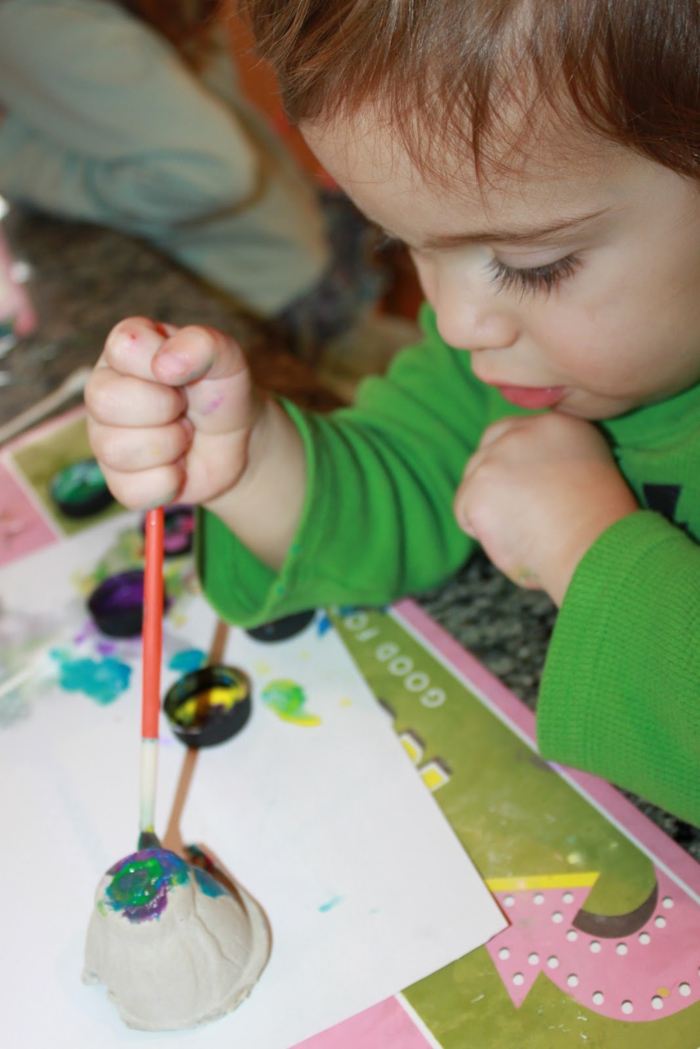 un enfant peint carton d'oeufs avec des peintures colorées - artisanat de Pâques avec des cartons d'oeufs