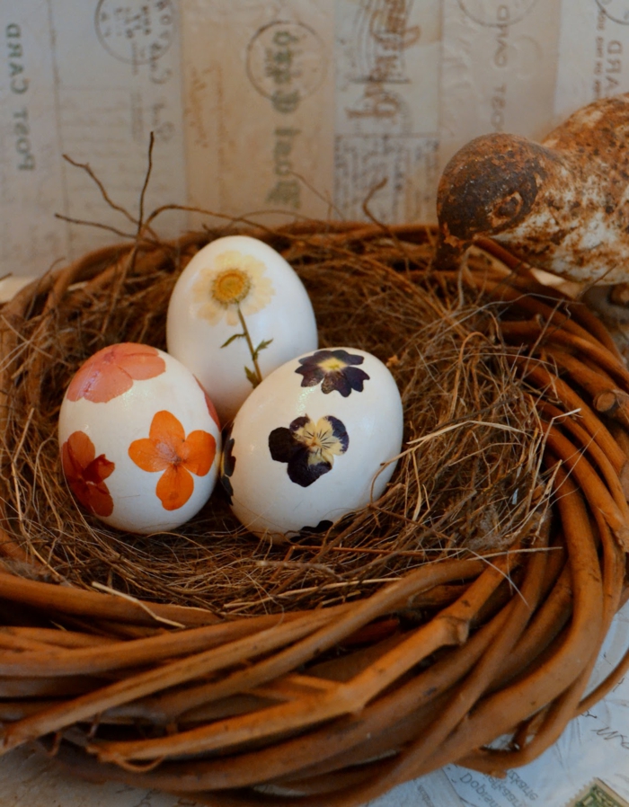 Oeufs de Pâques drôles peints avec différentes fleurs et placés dans le nid