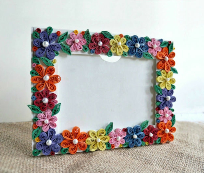 marco de fotos blanco decorado con flores de papel y perlas