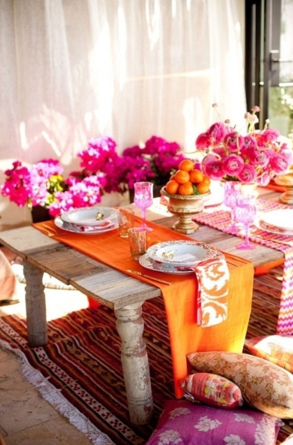 פרחים מודרניים רבים בצבעים בהירים, מנדרינות כתומות לפצות את השולחן