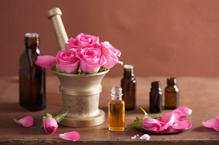 Tee kosmetiikkaa itsellesi: ruusuöljyä tummalta lasilta valmistetuissa kosmeettisissa pulloissa, ruusuhelmet, ruusut, laasti