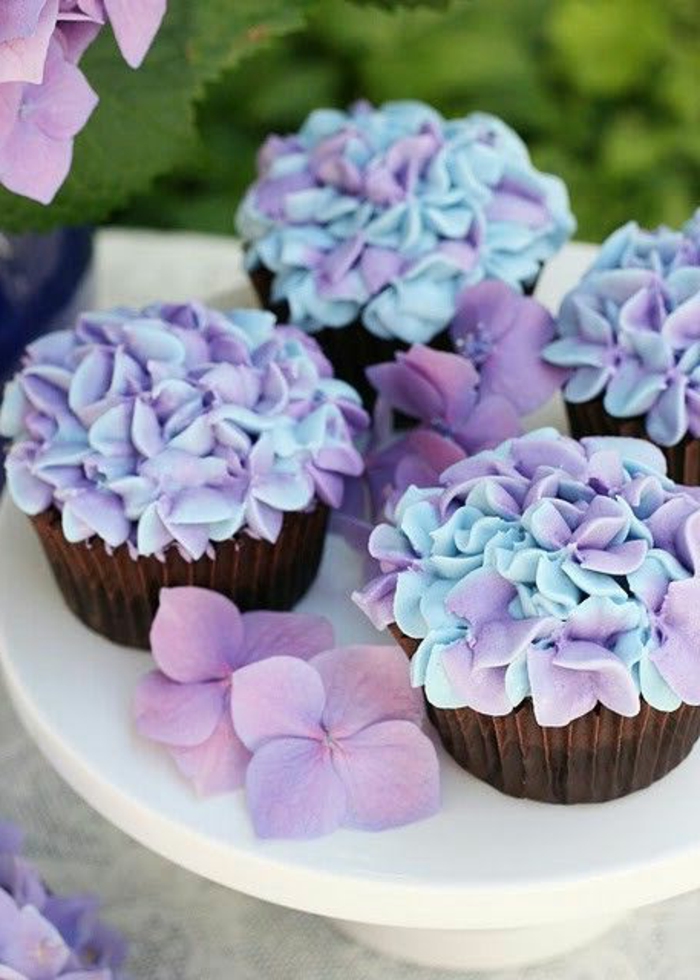 नीली और बैंगनी सजाने में क्रीम के फूलों के साथ मफिन