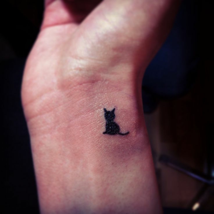 कलाई पर एक छोटी काली बिल्ली टैटू के लिए विचार - यहाँ एक काला मुर्गा के साथ एक छोटी सी बिल्ली है