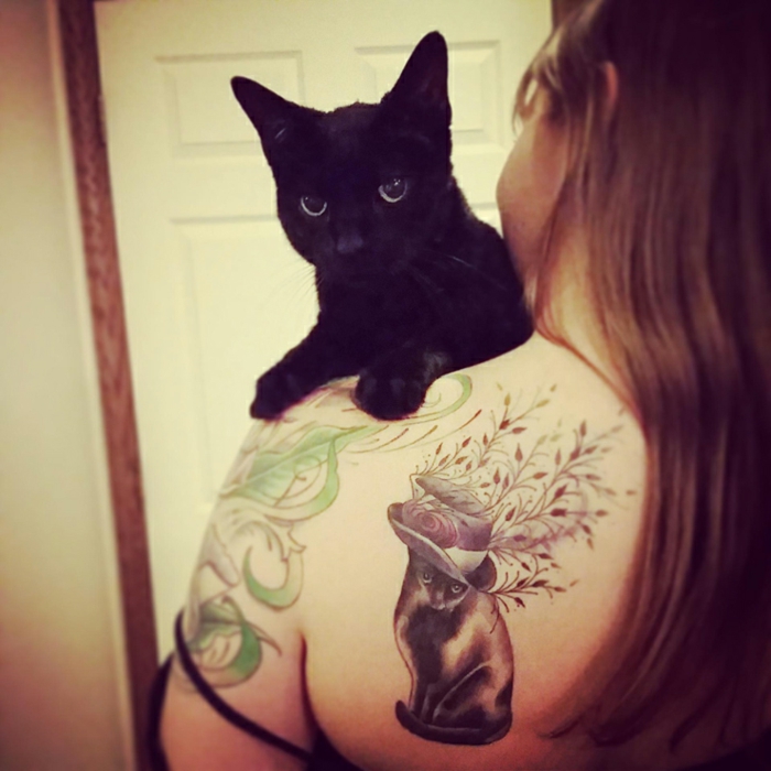هنا سوف تجد فكرة عن وشم القط - هنا قطة سوداء وامرأة مع وشم على الكتف مع قطة سوداء وقبعة ونباتات
