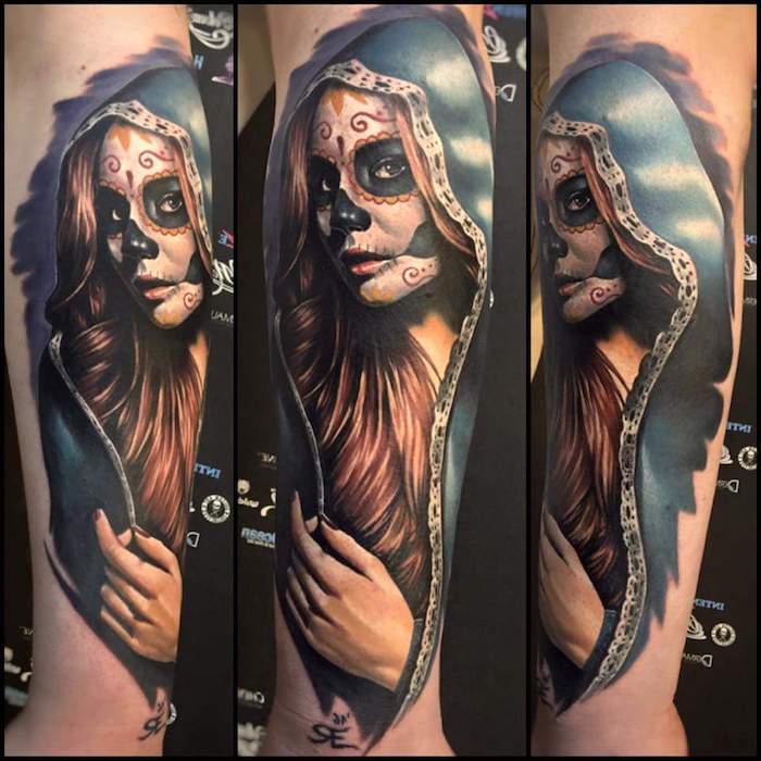 Χέρι με ένα μεγάλο τατουάζ La Catrina με μια νεαρή αποθανόντα γυναίκα με μαύρα μάτια και μαύρη μύτη και ένα κόκκινο νυχιών