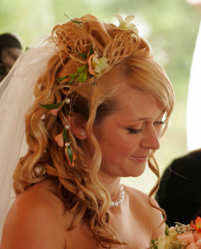μια νύφη με μεσαιωνικό χτένισμα - πλεγμένη στο πλάι με αξεσουάρ για τα μαλλιά σε ξανθά μαλλιά