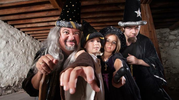 जादूगरों का एक पोशाक समूह - दो लड़के, एक लड़की और एक दादा
