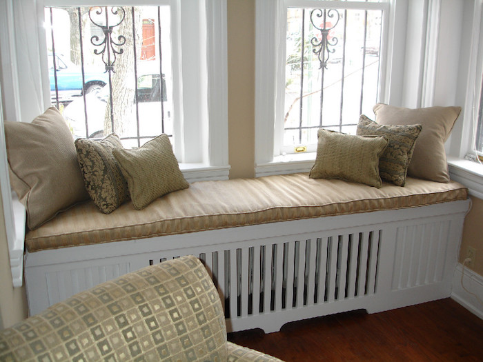 Радиаторно покритие във формата на диван с няколко пухкави възглавници