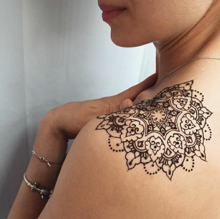 Γυναίκα με τατουάζ ώμου της χέννας, τατουάζ μαντάλα σε μαύρο χρώμα, ασημένια βραχιόλια