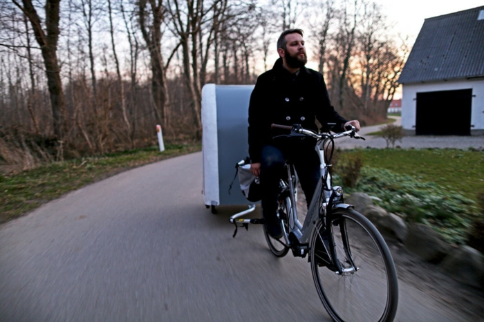 ποδηλάτης με μαύρο παλτό και ποδήλατο με τροχόσπιτο ποδηλάτου