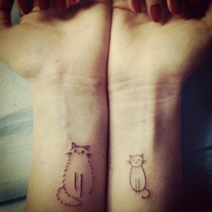 कलाई पर दो हाथ और दो छोटी काली बिल्ली टैटू हैं