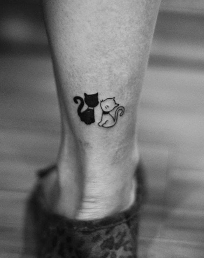 बिल्लियों के टैटू के विषय पर हमारे विचारों में से एक और पैर - एक काली बिल्ली और काली कंपन के साथ एक छोटी सी सफेद बिल्ली