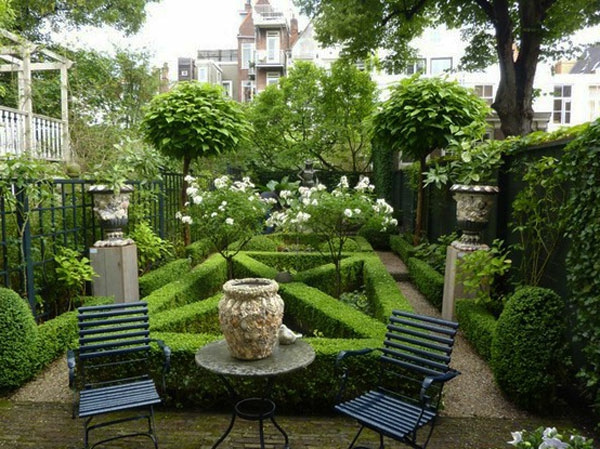 vihreä puutarha, jossa on kaksi mustaa tuolia ja monia vihreitä kasveja