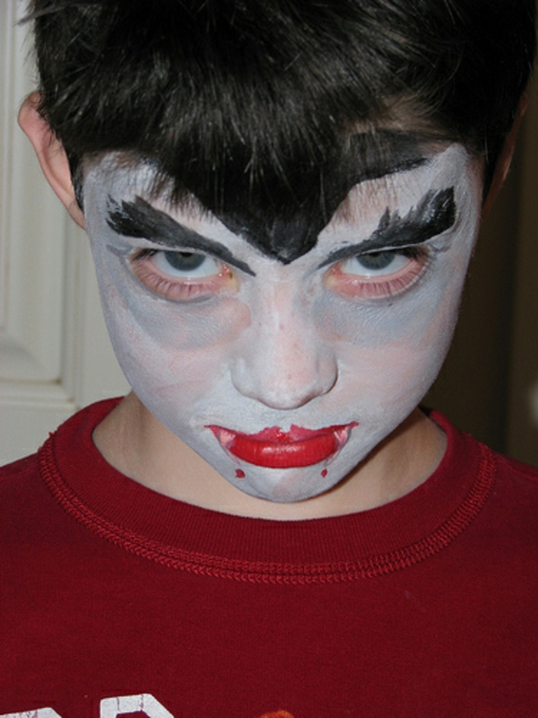 孩子吸血鬼脸化妆在红色的嘴唇