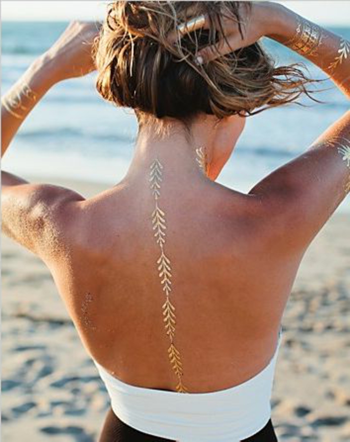 tatuointi ideoita hienovarainen viiva kultaisella värillä takana nainen vaaleat hiukset rannalla