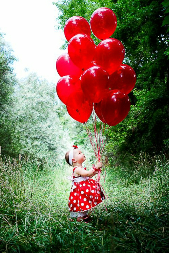 छोटी लड़की लाल गुब्बारे