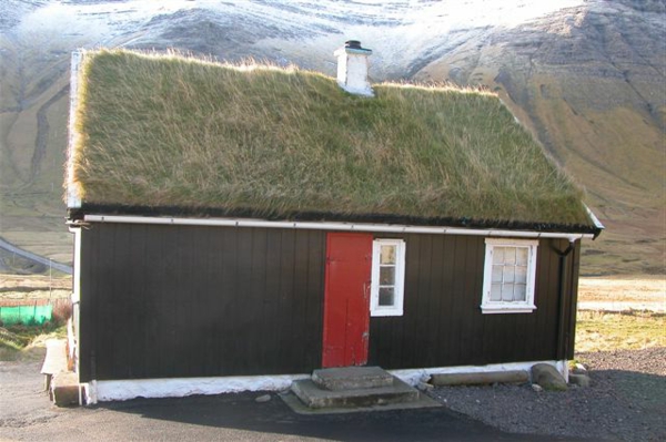 construcción de una pequeña casa con un techo interesante: montañas detrás