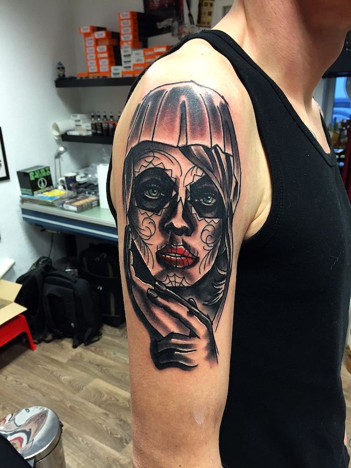 που σημαίνει la catrina - ένας άνδρας με ένα χέρι που κρατάει ένα μεγάλο μαύρο τατουάζ με μια νεαρή γυναίκα με κόκκινα χείλη, πράσινα μάτια