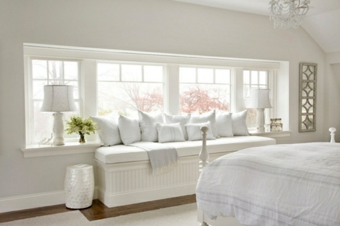 Dormitorio blanco sentado en las lámparas y almohadas de la repisa de la ventana