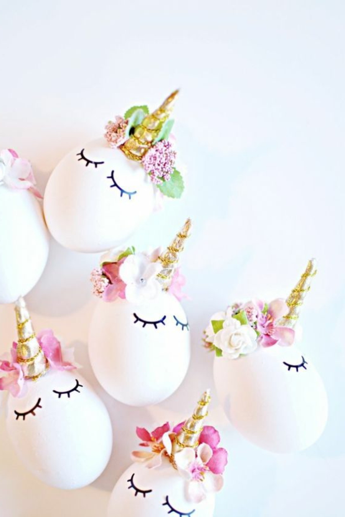 Oeufs blancs drôles comme des licornes avec des cornes dorées et des fleurs pour la décoration