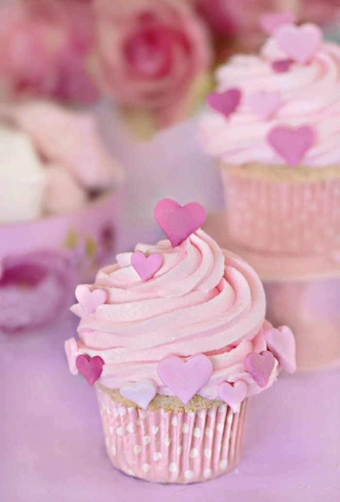 गुलाबी फॉन्डंट और क्रीम के दिल से सजाए गए कप केक