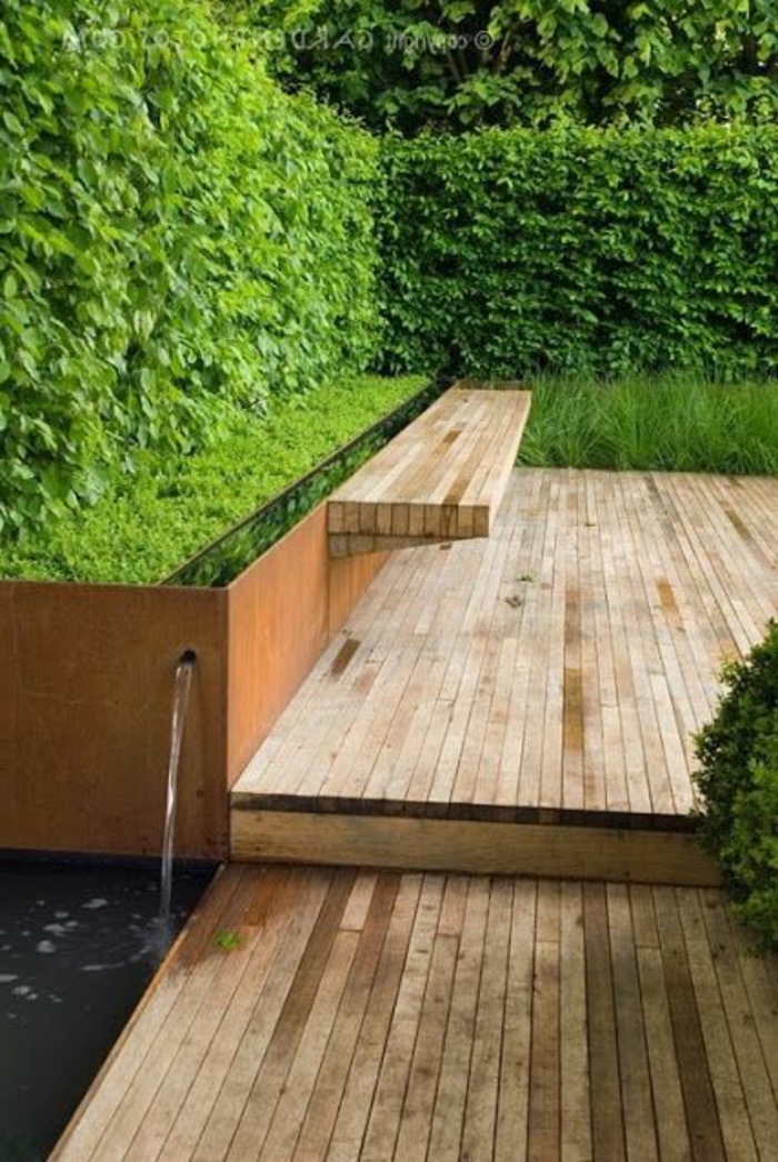 Característica del agua, banco incorporado Agua característica un seto verde - jardín purista