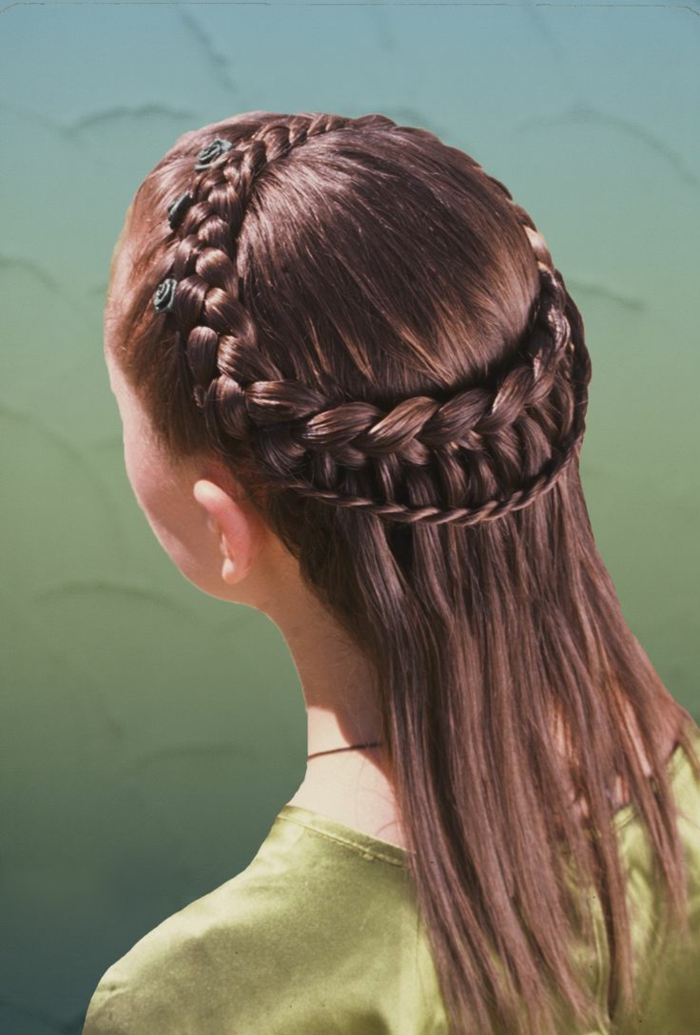 ένα λεπτό κομμωτήριο κοριτσιών μέσης ηλικίας από καστανά μαλλιά με πράσινα λουλούδια ως αξεσουάρ για τα μαλλιά