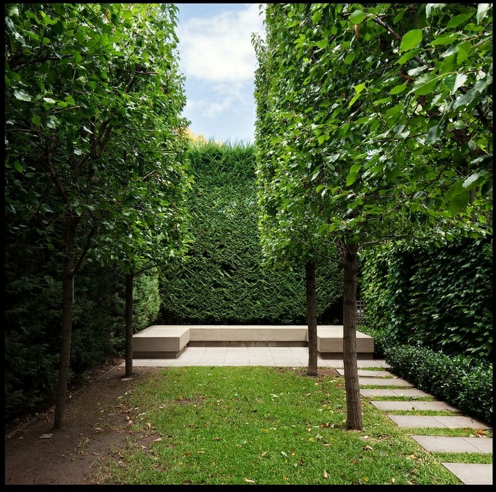 un jardín delantero verde moderno con árboles y pantallas de seto, área de descanso