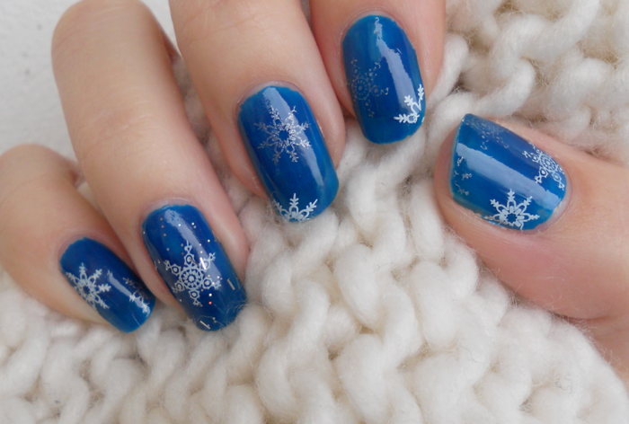 Λευκές και ασημένιες νιφάδες χιονιού σε σκούρο γαλάζιο έδαφος, στρογγυλό σχήμα νυχιών, σχέδιο χειμωνιάτικων νυχιών