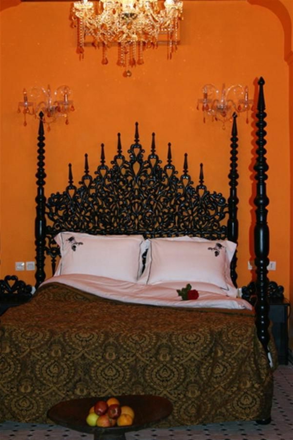 नारंगी दीवार के डिजाइन के साथ लक्जरी ओरिएंटल बेडरूम में अमानक रूप से दिखने वाला हेडबोर्ड