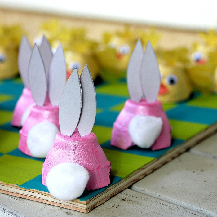 Bricoler avec des boîtes d'oeufs dans des lapins de Pâques de couleur rose par derrière