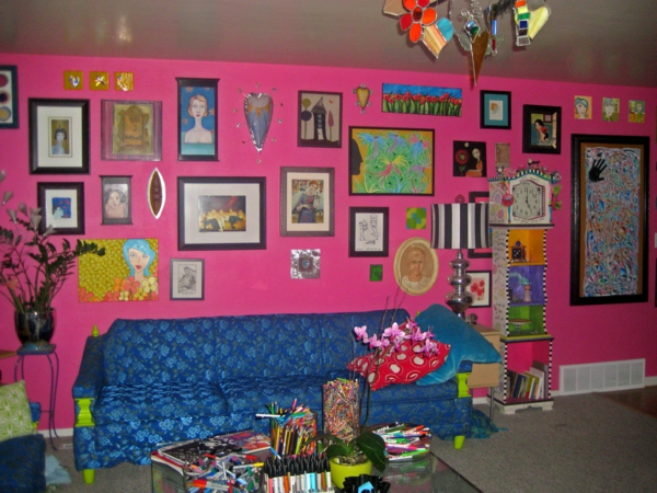 ροζ-τοίχο-ζωγραφική-και-πολλές-εικόνες-στον τοίχο-καναπέ σε μπλε χρώμα