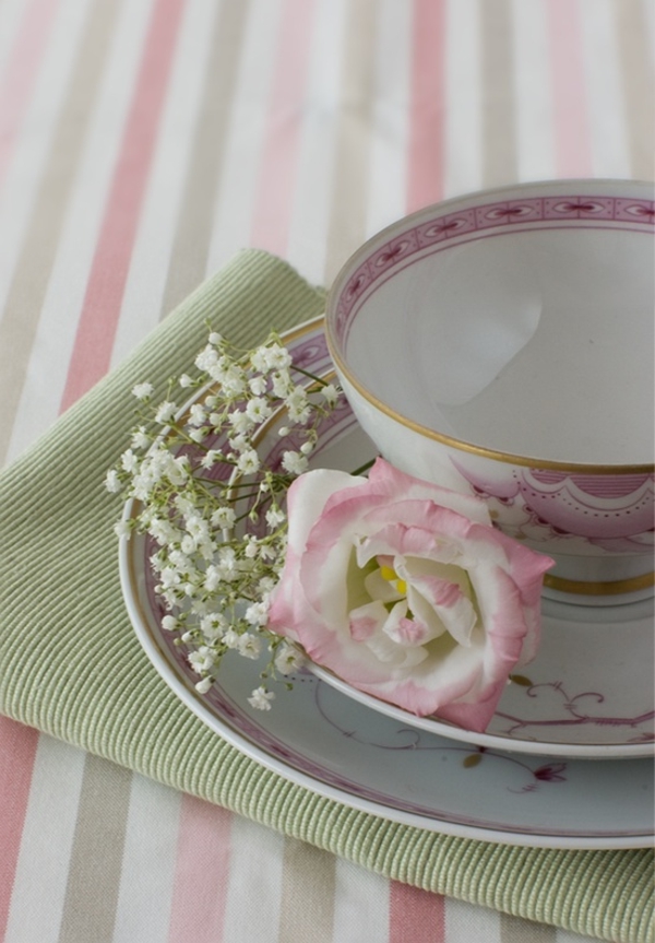 שולחן לקשט עם שמיכה ורודה יפה וצלחת חרסינה עם פרחים לבנים
