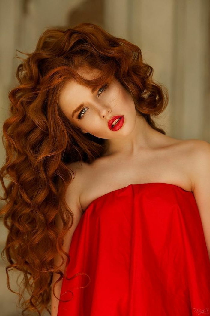 cabello color cobre, hermosos rizos, labios rojos, vestido rojo, con los brazos desnudos