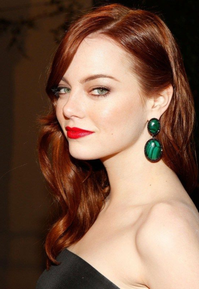 铜红色的头发，醒目的绿色耳环强调绿色的眼睛，白皙的皮肤，鲜艳的红色唇膏