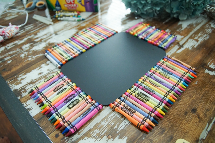 Lindos útiles escolares: lápices de colores como el arco iris rodean una pizarra negra