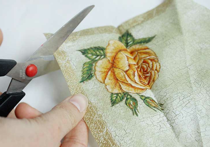नैपकिन तकनीक - यहां कैंची की एक जोड़ी और पीले गुलाब के साथ एक नैपकिन है