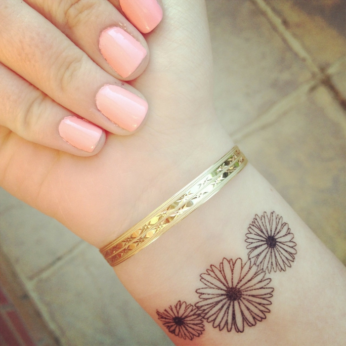hienovarainen tatuointi suunniteltu muodossa kolme kaunista pieniä kukkia kultainen rannekoru suuri manikyyri