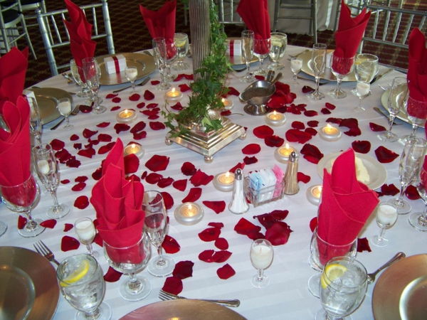 servilletas rojas en el techo blanco vidrioso y pétalos de rosas rojas - ideas para la decoración del partido