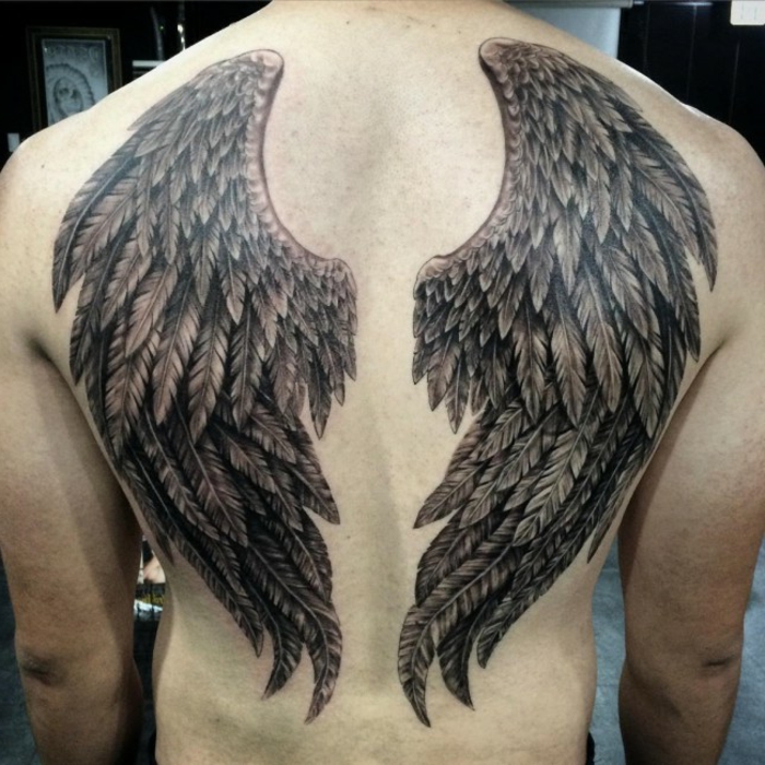 一个男人和他的天使纹身与两个长长的黑色羽毛的黑色天使翅膀
