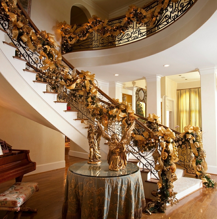 decoración dorada de escalera para Navidad con volúmenes, luces de hadas y ángeles sobre la mesa